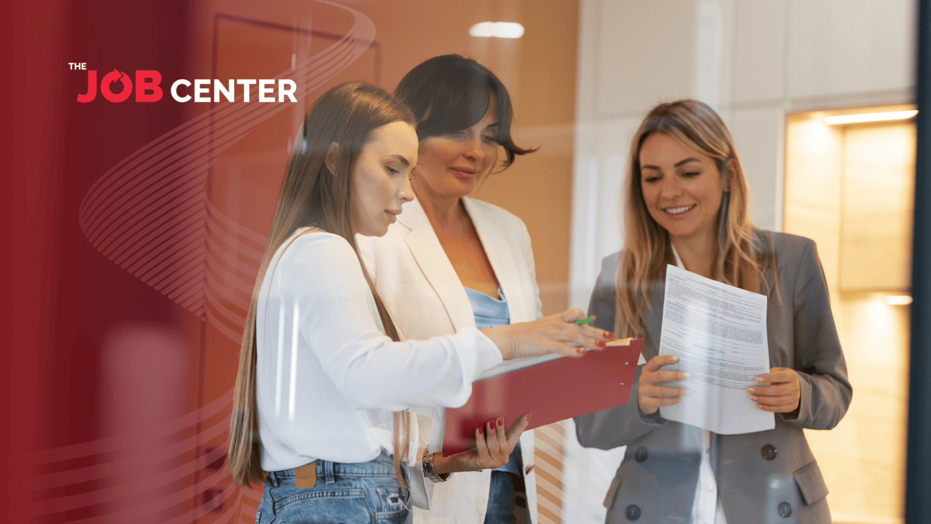 Woman in corporate attire holding a printed form discusses resumes with coworkers