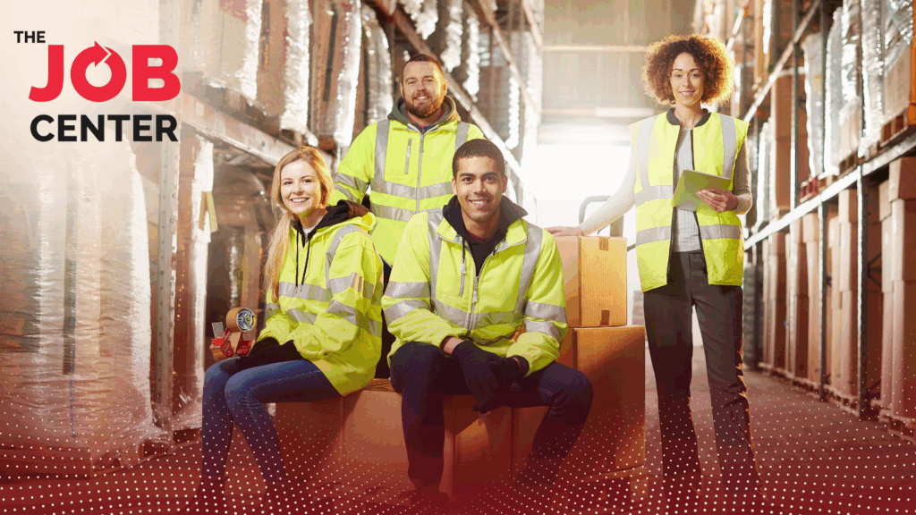 Four warehouse workers smile in a warehouse
