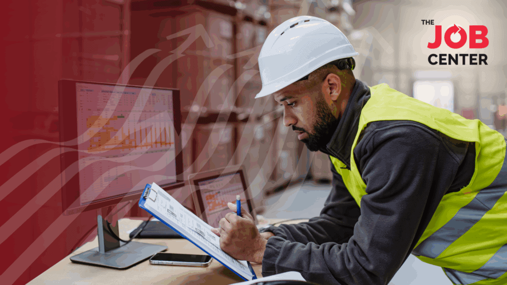 Night shift warehouse worker looks at a clipboard at a desk in the warehouse