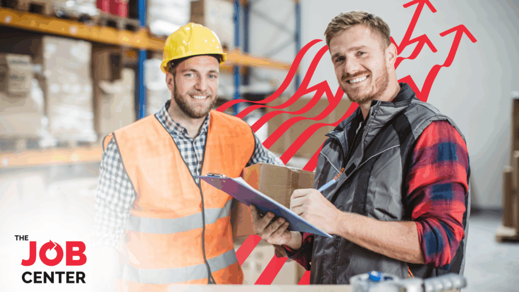 Two light industrial employees stand smiling in their workplace